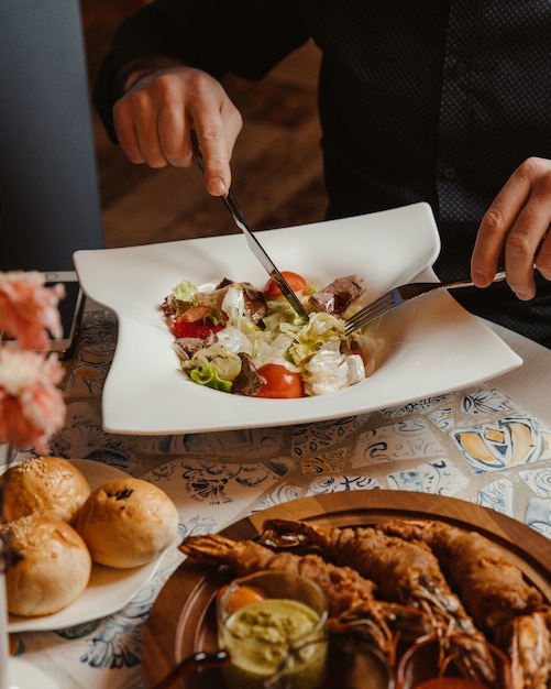 Free Photo man eating caesar salad with mixed ingredients