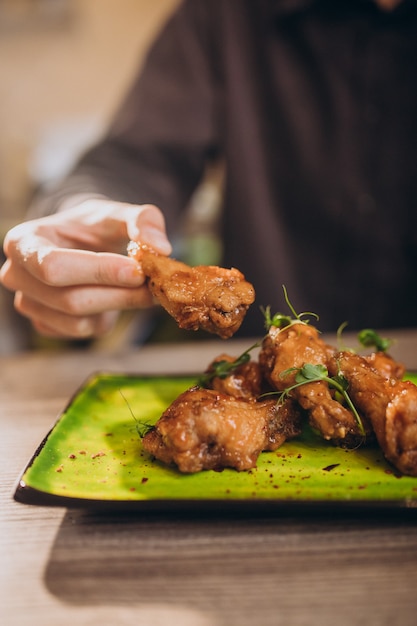 Free photo man eating fried chicken with sauce in a cafe