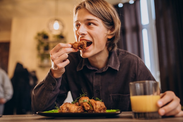 Free photo man eating fried chicken with sauce in a cafe