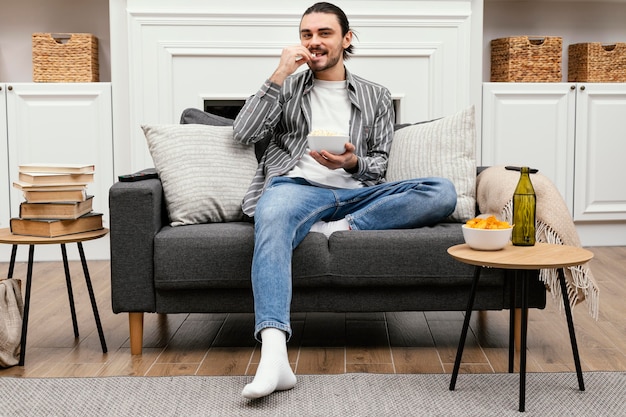 Man eating popcorn and watching tv long shot