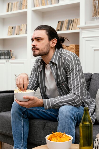 Man eating popcorn and watching tv side view