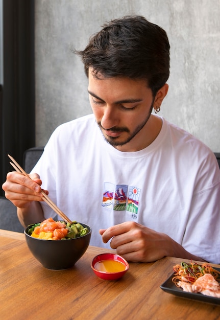 Free photo man eating salmon dish bowl at the restaurant