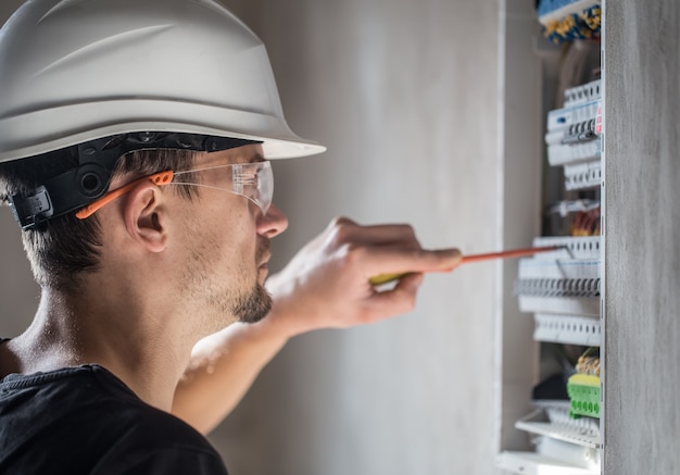 Free Photo man, an electrical technician working in a switchboard with fuses. installation and connection of electrical equipment. close up.