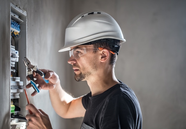 Free Photo man, an electrical technician working in a switchboard with fuses. installation and connection of electrical equipment.