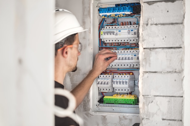 Free photo man, an electrical technician working in a switchboard with fuses. installation and connection of electrical equipment.