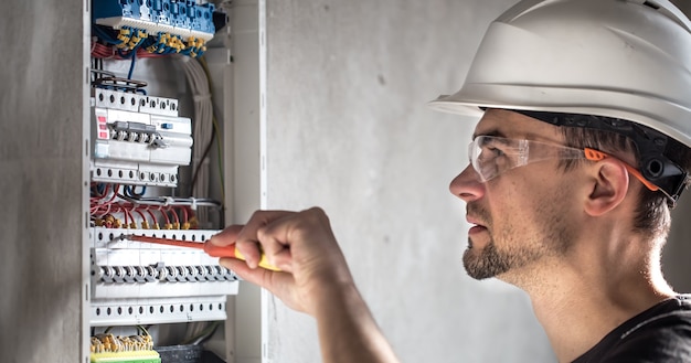 Free photo man, an electrical technician working in a switchboard with fuses. installation and connection of electrical equipment.