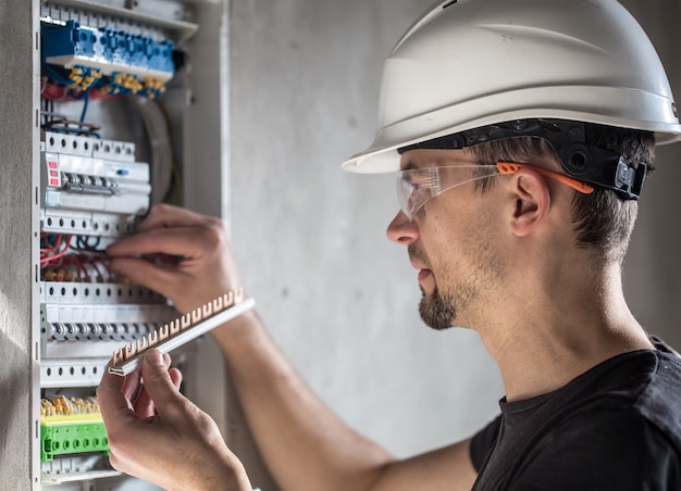 Free photo man, an electrical technician working in a switchboard with fuses. installation and connection of electrical equipment.