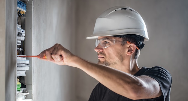 Free Photo man, an electrical technician working in a switchboard with fuses. installation and connection of electrical equipment.