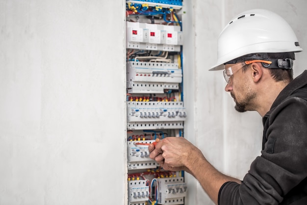 Free Photo man, an electrical technician working in a switchboard with fuses. installation and connection of electrical equipment.