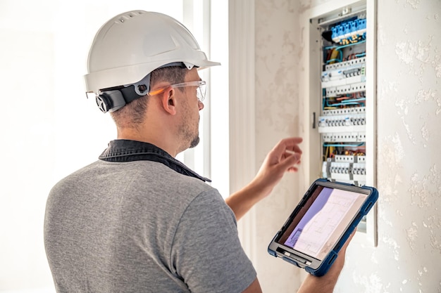 Free Photo man an electrical technician working in a switchboard with fuses uses a tablet