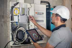 Free photo man an electrical technician working in a switchboard with fuses uses a tablet