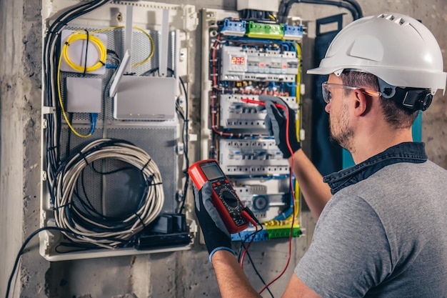 Man an electrical technician working in a switchboard with fuses