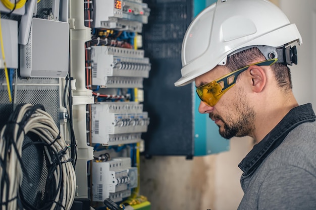 Man an electrical technician working in a switchboard with fuses