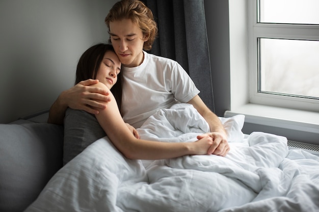 Man embracing girlfriend while in bed