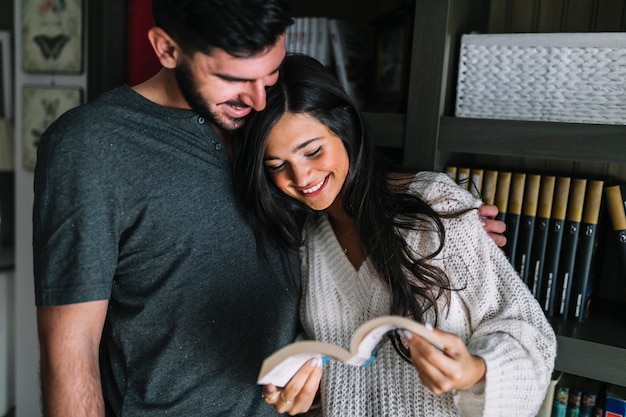 Free photo man embracing her girlfriend looking in book