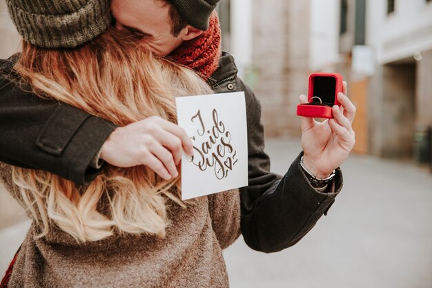 Man embracing woman and holding ring