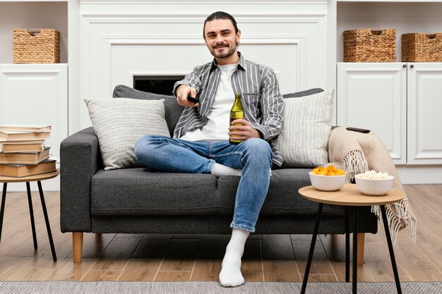 Man enjoying a beer and watching tv sitting on the couch