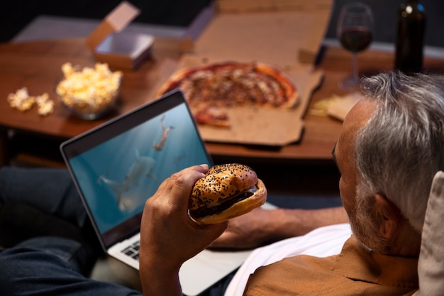 Free photo man enjoying a burger while being home alone