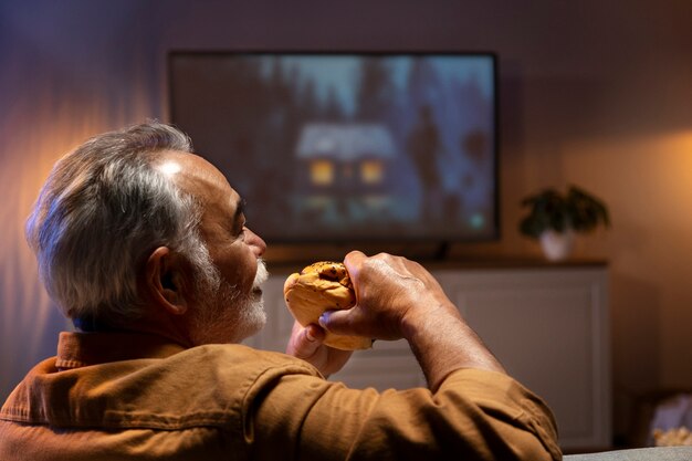 Man enjoying food while being home alone and watching tv