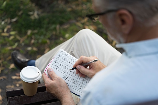 Free photo man enjoying a sudoku game on paper by himself