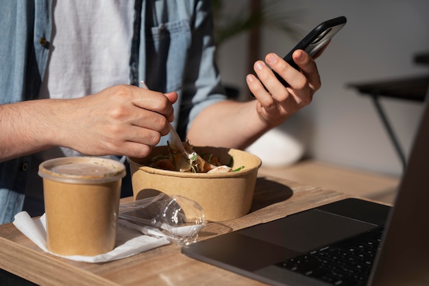 Man enjoying takeaway food and using smartphone