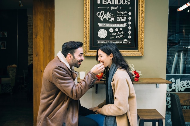 Free Photo man feeding woman in outdoor cafe