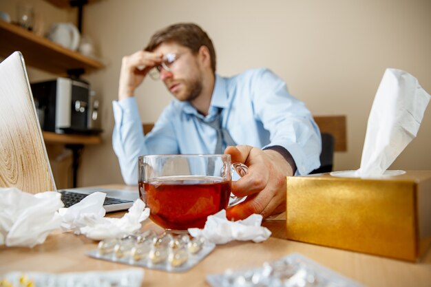 Man feeling sick and tired, drinking tea