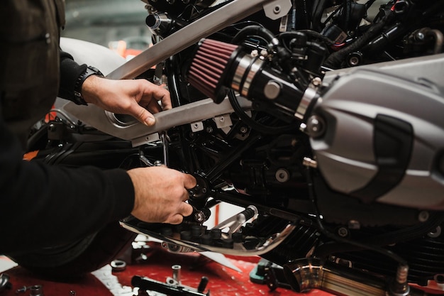 Free photo man fixing a motorcycle in a modern workshop