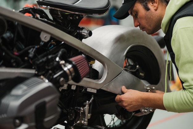 Free photo man fixing a motorcycle in a modern workshop