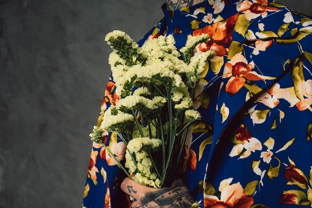 Man in floral suit holding yellow limonium flower in hand