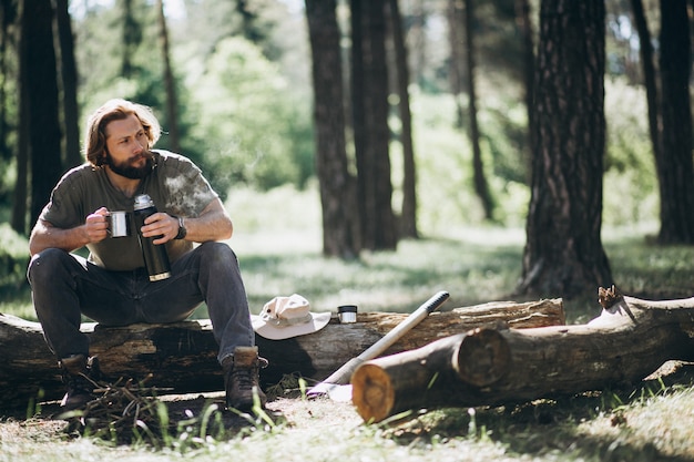 Free photo man in forest with tea by fire