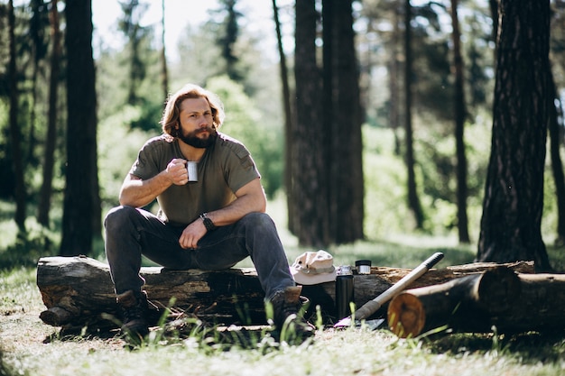 Free photo man in forest with tea by fire