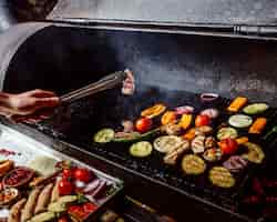 Free photo a man fries grilled vegetables with sausages