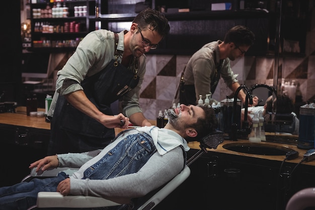 Free photo man getting his beard shaved with razor