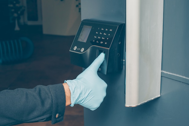 Free Photo a man getting intercom to read his fingerprint to open the door with gloves on.  