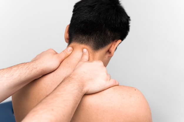 Free photo man getting neck massage for pain from physiotherapist