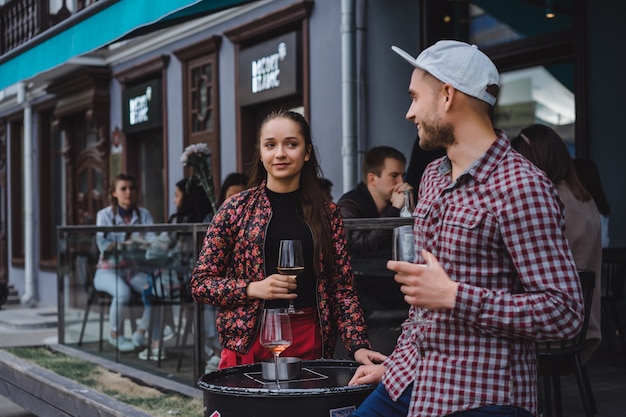 Free photo a man and a girl are drinking wine on a summer terrace in a street cafe. stylish couple drinking wine in cafe