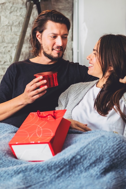 Man giving gift box to woman on couch 