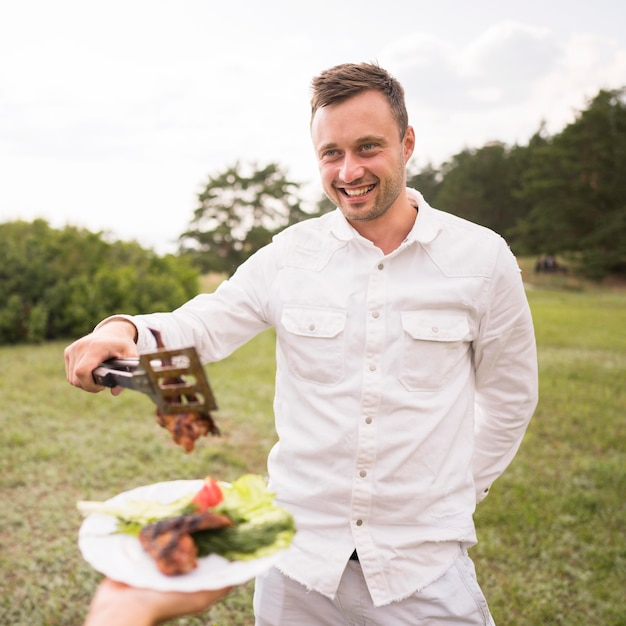 Man giving steak to person for barbecue