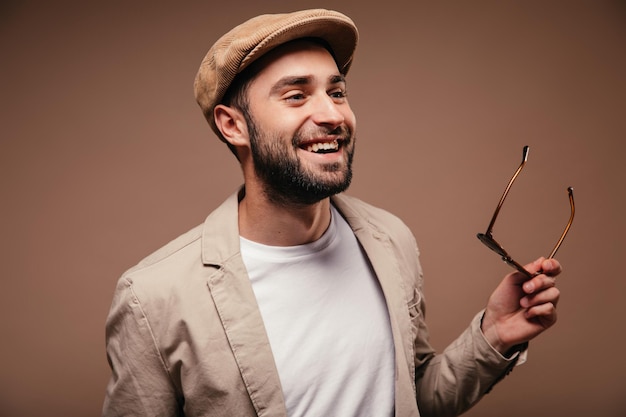 Free photo man in good mood posing on brown background and holding glasses