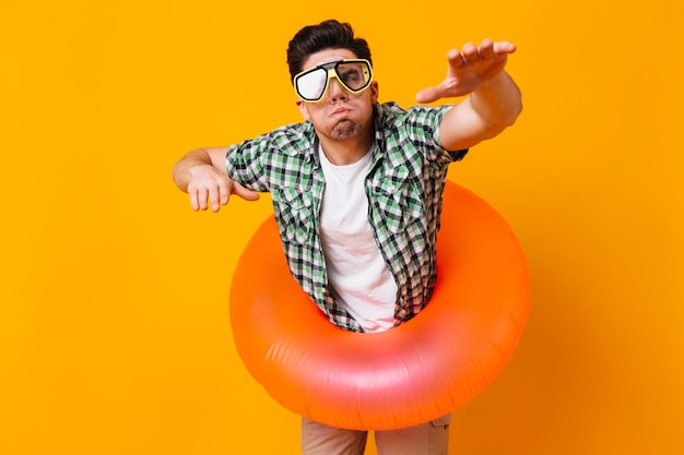 Man in green shirt, diving mask and inflatable circle represents swimming on orange space.