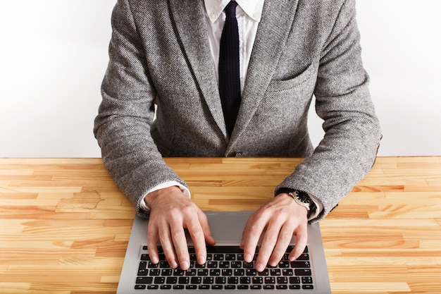 Man in grey office suit types something on the keyboard