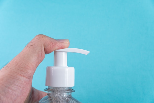 Man hand in container with alcohol gel on the light blue