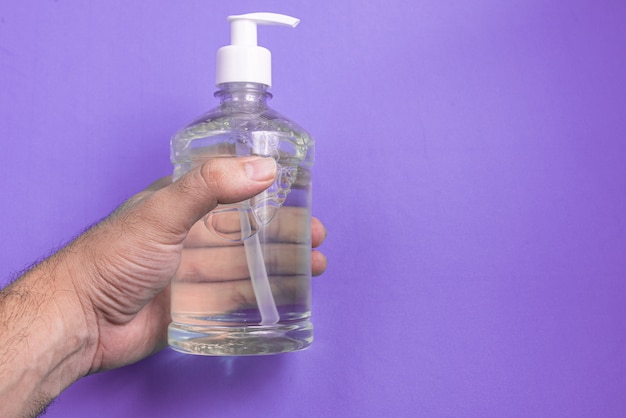 Man hand in container with alcohol gel on the light blue