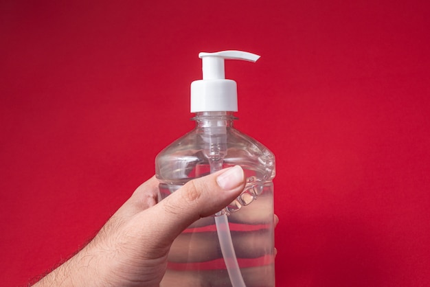 Man hand in container with alcohol gel on the red wall