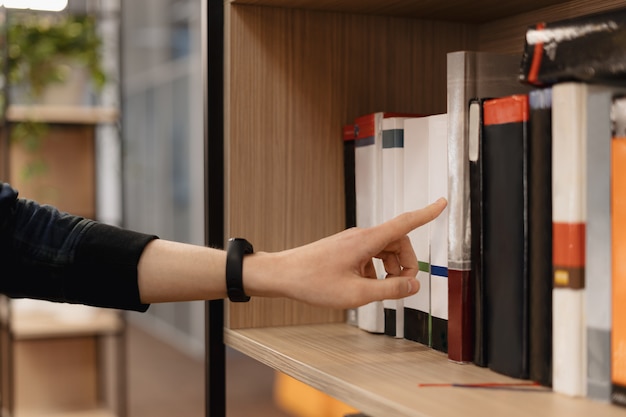 Man hand picking books from the shelf