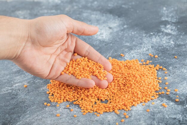 Man hand taking a heap of raw lentils.