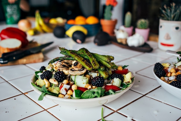 Free photo man hands holding big deep plate full of healthy paleo vegetarian salad made from fresh organic biological ingredients, vegetables and fruits, berries and other nutritional things