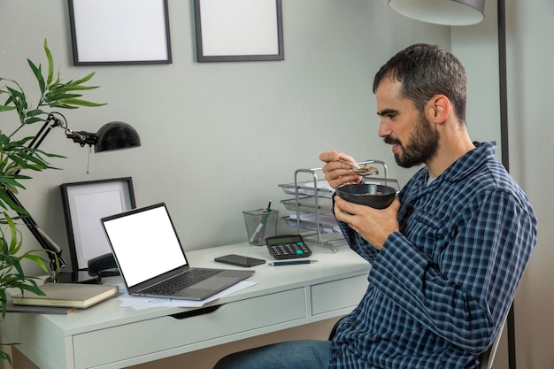 Free photo man having breakfast while working from home