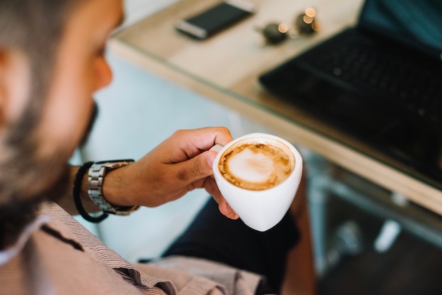 Free photo man having cappuccino at laptop